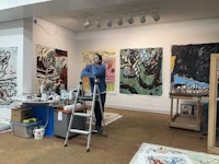 a man standing on a ladder in an art studio
